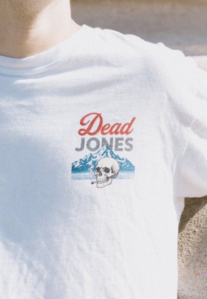 Close-up of the small Dead Jones Band skull and mountain chest graphic on a white T-shirt.