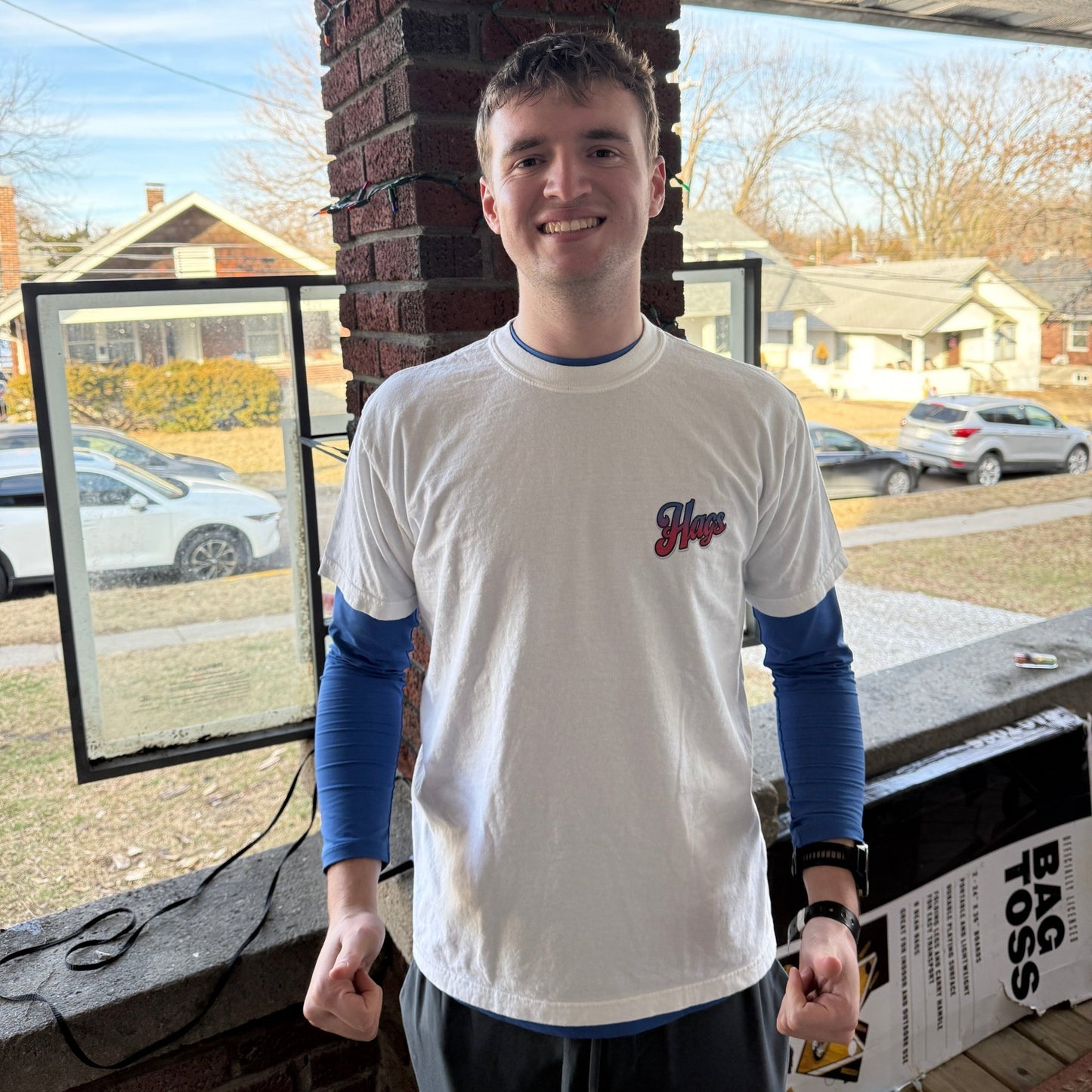 Man wearing the white HAGS Have a Great Semiquincentennial T-shirt, showing the small red and blue chest graphic.