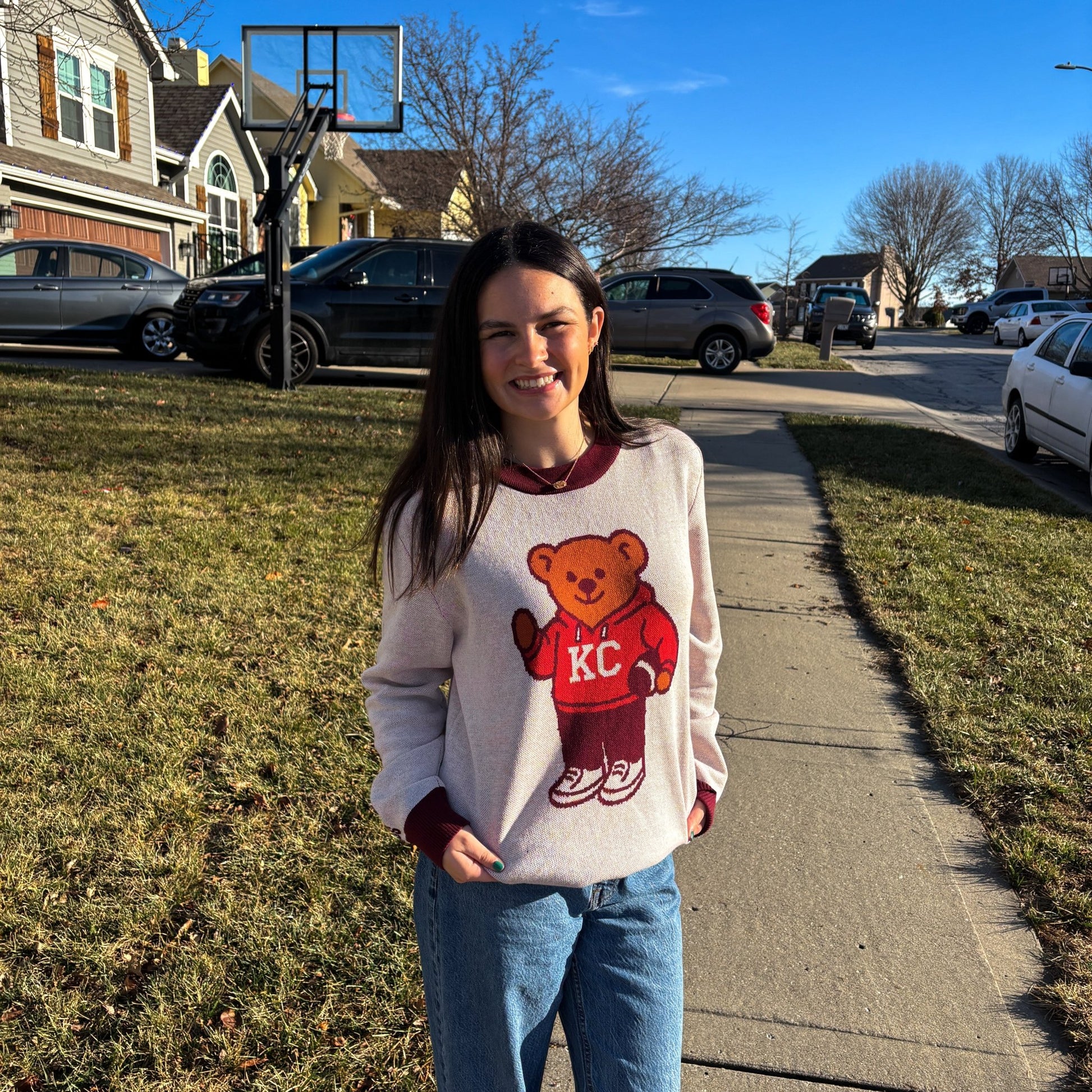 Woman wearing the white HAGS Kansas City KC bear knit sweater with burgundy trim outdoors.