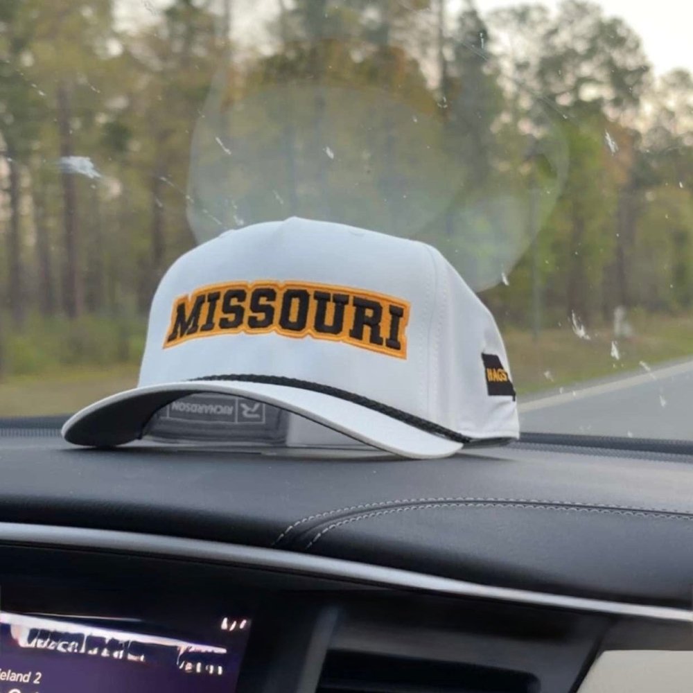 White HAGS Missouri rope hat with black and gold lettering resting on a vehicle dashboard.