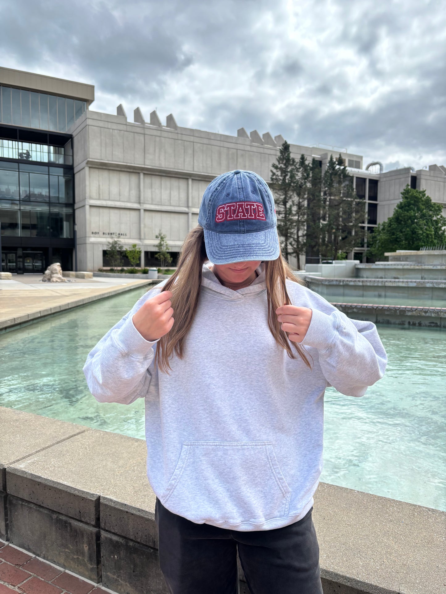 Person wearing a washed navy HAGS STATE embroidered dad hat outdoors.