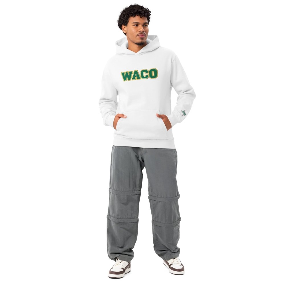 Model wearing a white HAGS Waco Texas hoodie with green WACO chest lettering.